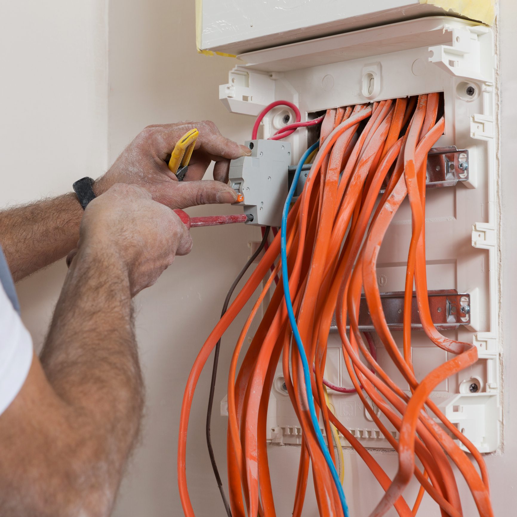 Electrician working on electrical panel wiring.