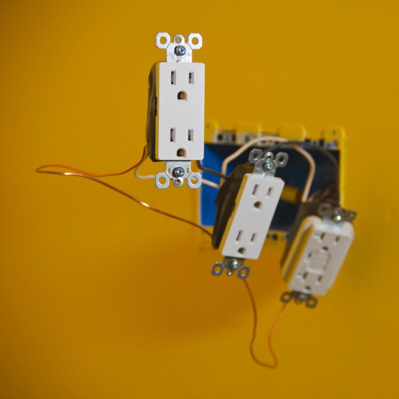 Electrical outlets with exposed wiring on wall.