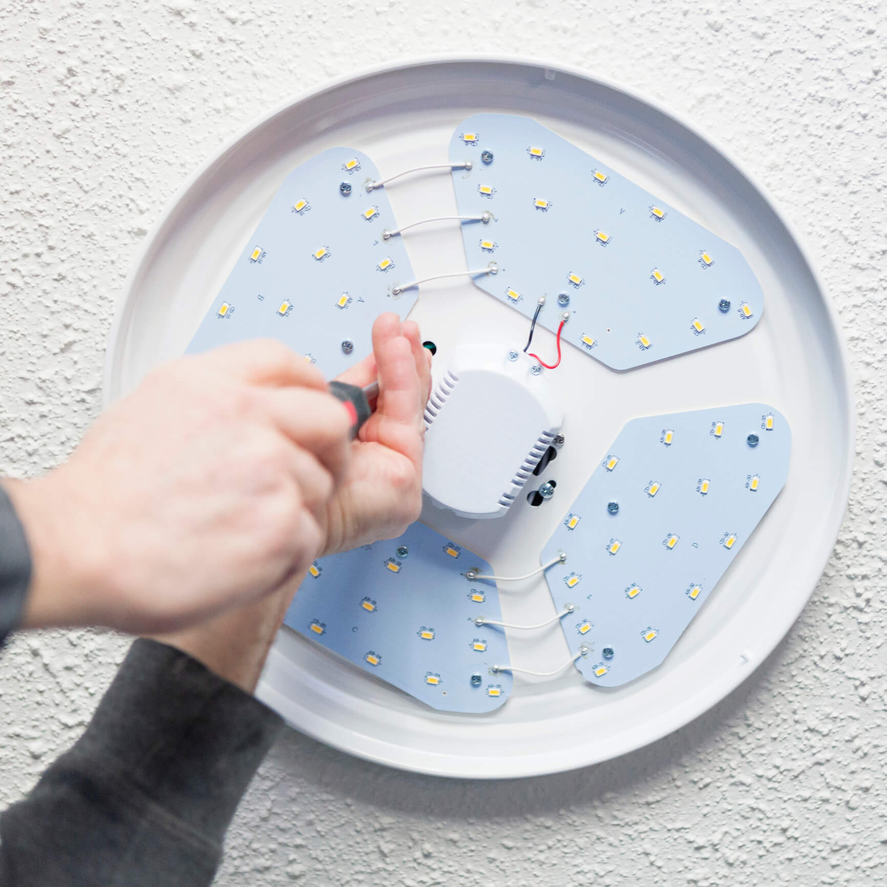 Installing LED light fixture on ceiling.